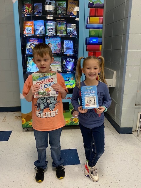 kids holding books in front of vending machine