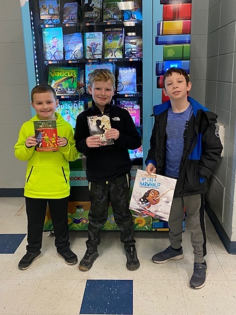 boys holding books in front of vending machine