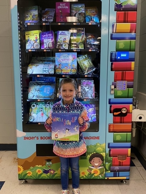 student holding book in front of vending machine