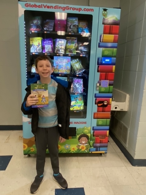 student holding book in front of vending machine